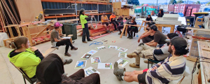 Para Kore facilitator leading a zero waste workshop for tradies focused on reducing building waste, held in a timber workspace with participants seated in a circle